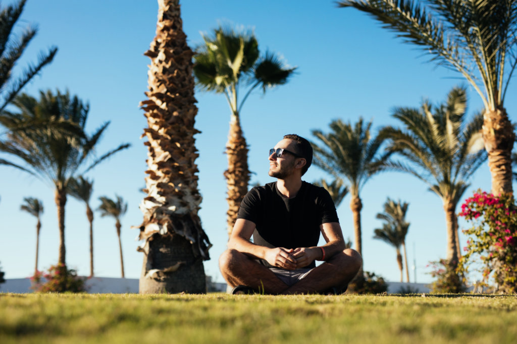 bearded man sunglasses sitting grass palms summer vacation luxary resort